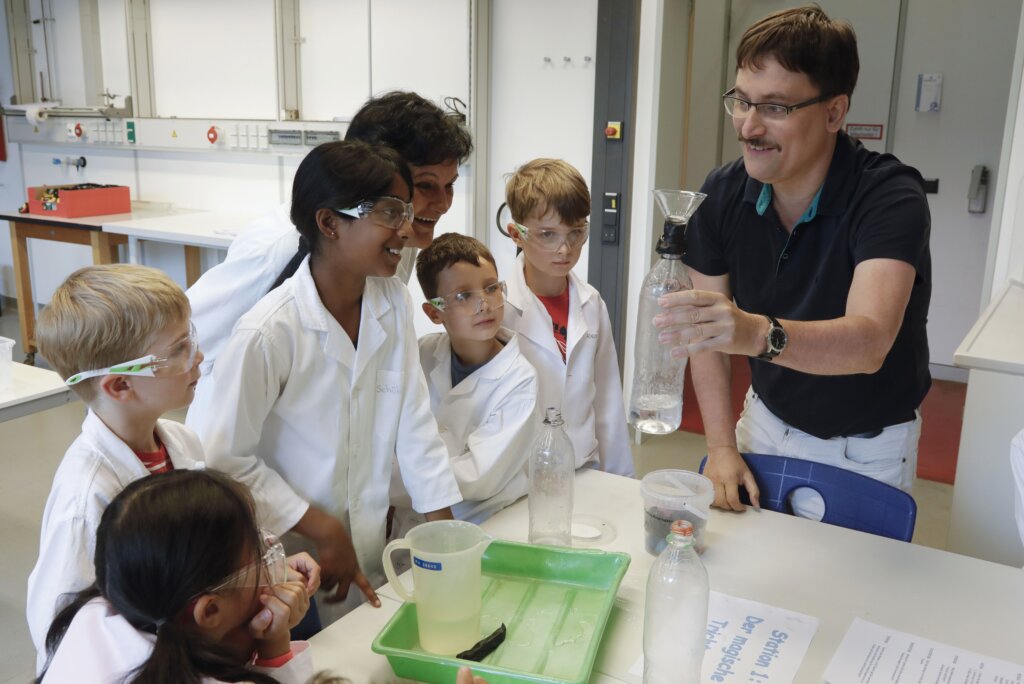 Ein Erwachsener mit Kindern beim experimentieren in einem Labor